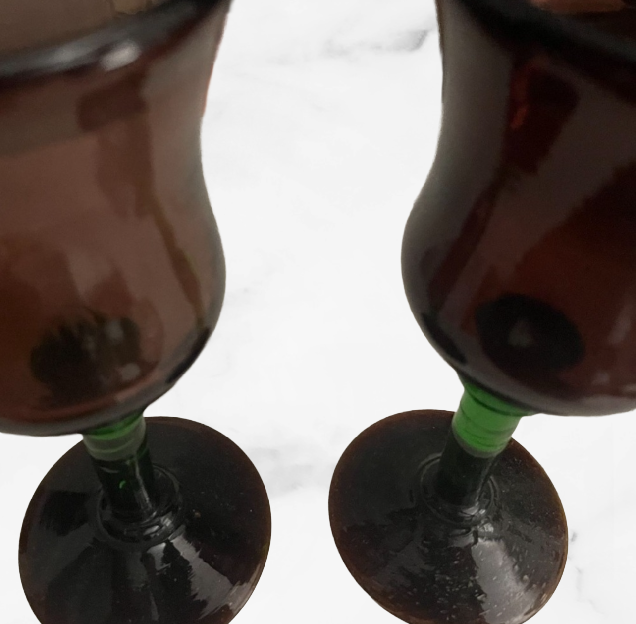 Two glasses filled with a dark liquid on a marble surface