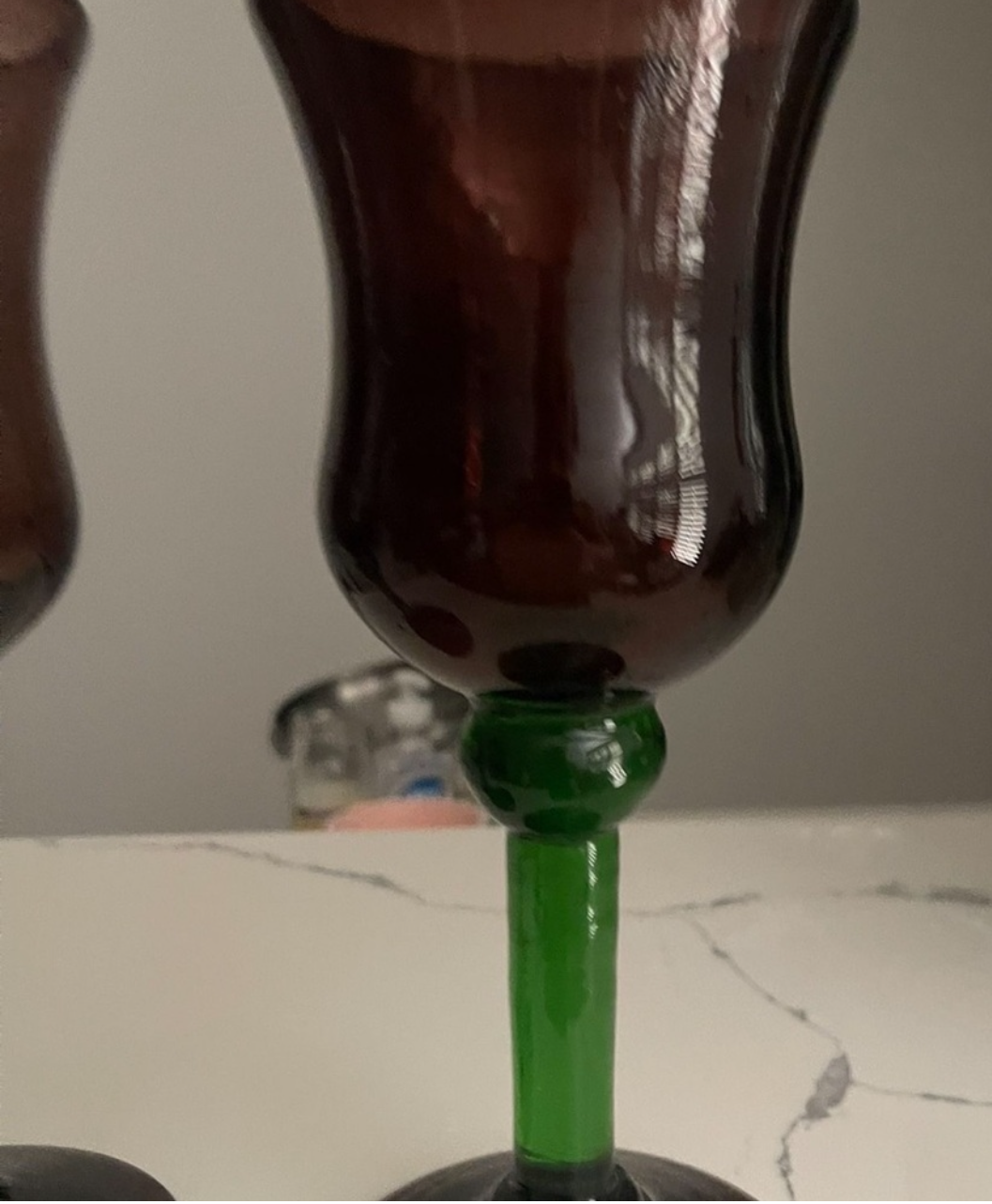 Close-up of a glass bottles from estate sale being filled with a dark liquid, likely soda, on a marble surface.